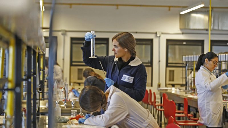 Jóvenes educadoras dentro de un laboratorio, una de ellas observa un tubo